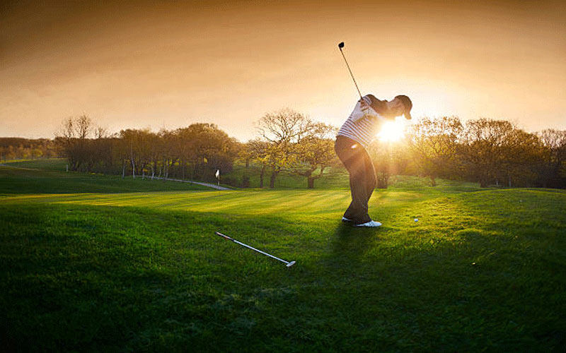 A golfer swings in the morning