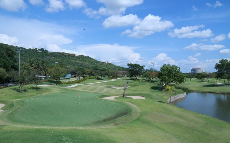 Scenic golf green surrounded by rolling hills, trees and water hazard at Bagan Nyaung Oo Golf Club in Myanmar