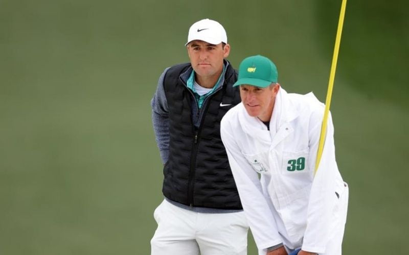 A caddy accompanies a golfer on golf course (The man in white coat)