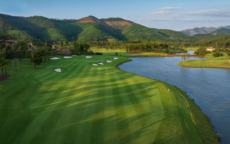Silk Path Dong Trieu Golf & Country Club featuring manicured fairways, a large lakeside water hazard, and mountain views in Quang Ninh, Vietnam