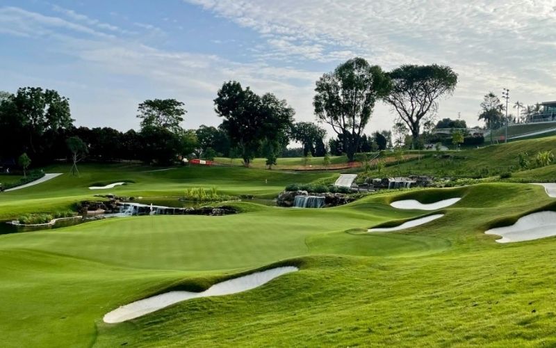 Singapore Island Country Club in Singapore featuring manicured greens, sand bunkers, and a waterfall landscape under a blue sky