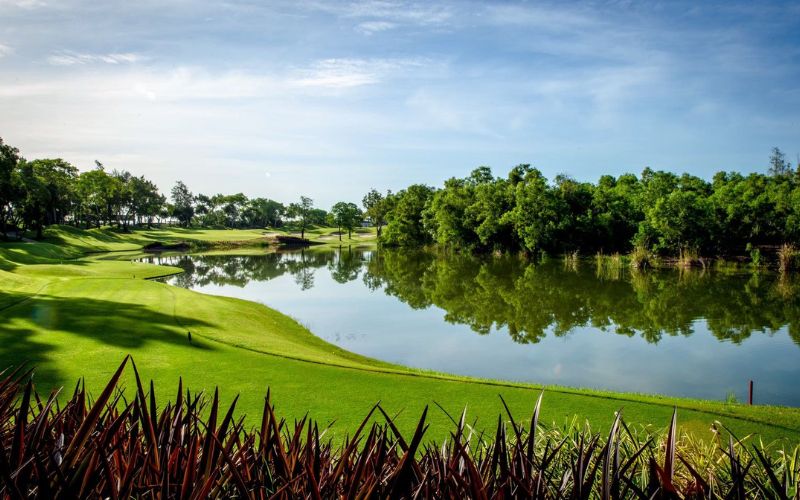 Tranquil view of Alpine Golf Sports Club, featuring a serene lake surrounded by lush green fairways, under a clear blue sky, showcasing the peaceful atmosphere of the golf course.