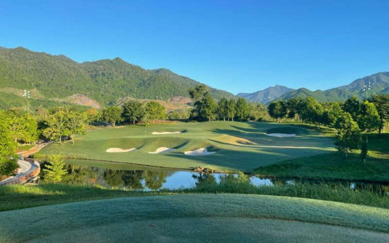 Ba Na Hills Golf Club with green fairways, sand bunkers, and surrounding mountain landscape.