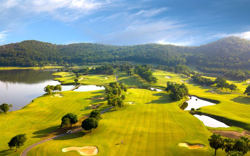 Chi Linh Star Golf & Country Club with bright green fairways, water hazards, and surrounding hills under a clear sky.