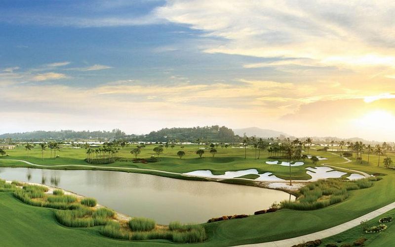 Legend Hill Golf Club in Vietnam with scenic fairways, water features, and a beautiful sunset sky over the course.