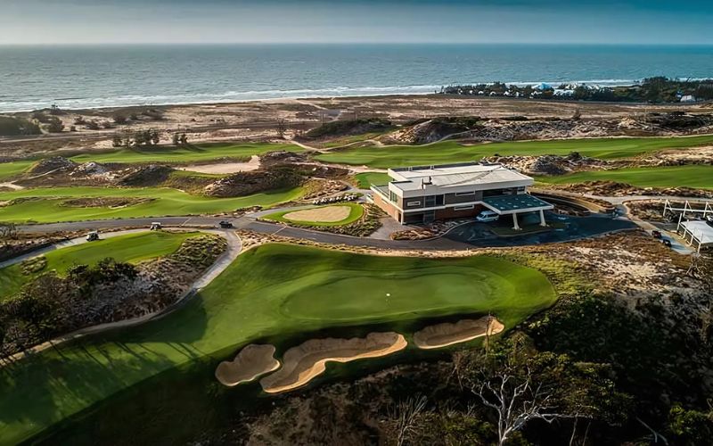 Panoramic view of The Bluffs Grand Ho Tram Strip golf course with coastal sand dunes and stunning ocean scenery.