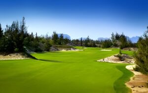 BRG Da Nang Golf Resort in Vietnam with bright green fairways, coastal dunes, and clear blue sky.