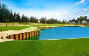 BRG Da Nang Golf Resort with bright green fairways, clear blue water, and golden sand under a sunny sky.