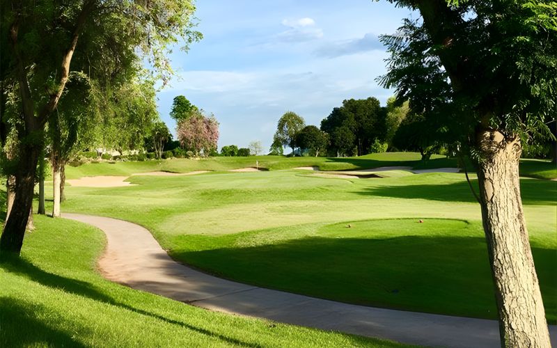 Beautiful view of Burapha Golf Club with smooth fairways, lush green grass, and trees lining the course under a clear, sunny sky.