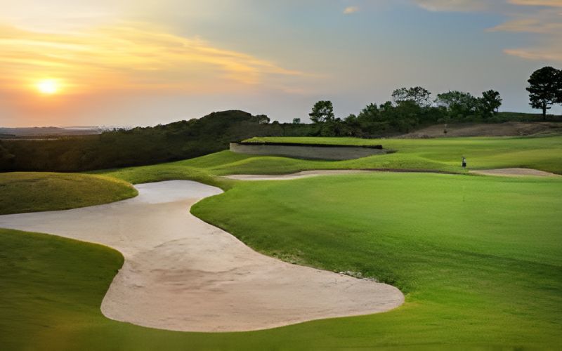 Scenic view of Burapha Golf Club in Pattaya, Thailand, featuring lush green fairways and sand bunkers at sunset.
