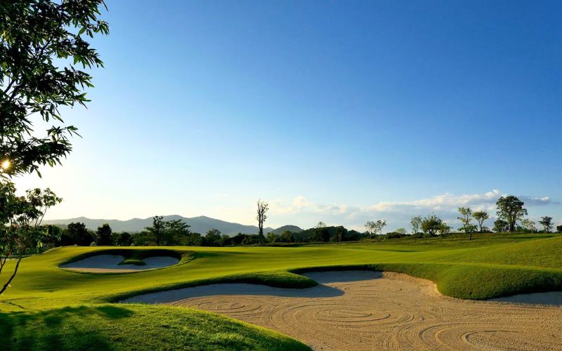 Scenic landscape of Chiang Mai Highlands Golf & Spa Resort with sand bunkers and distant mountains.