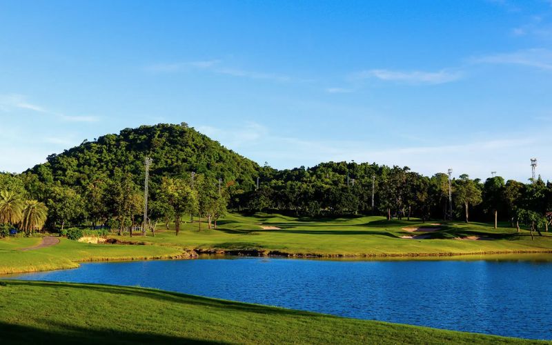 Peaceful golf course scene at Laem Chabang International Country Club featuring a lake and green hills.
