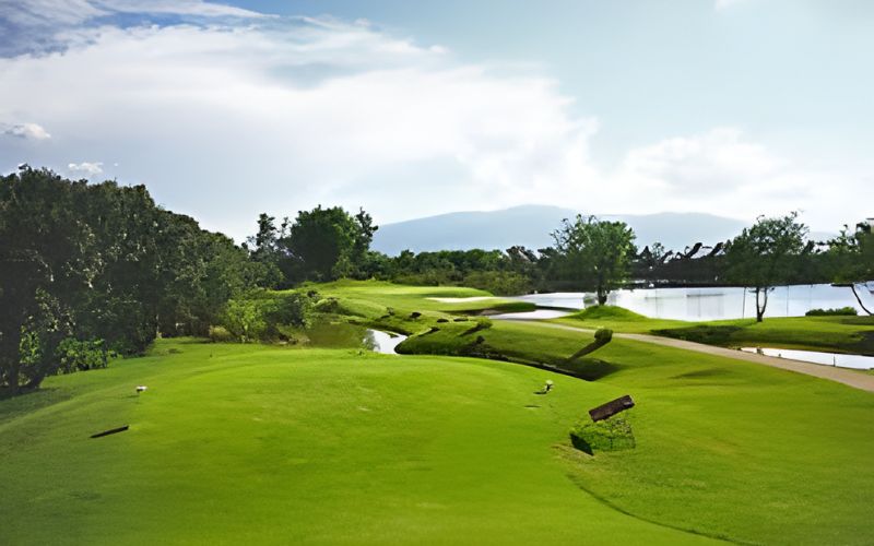 Scenic fairway view at Mae Jo Golf Club & Resort in Chiang Mai, surrounded by lush greenery and tranquil water features under a clear sky.