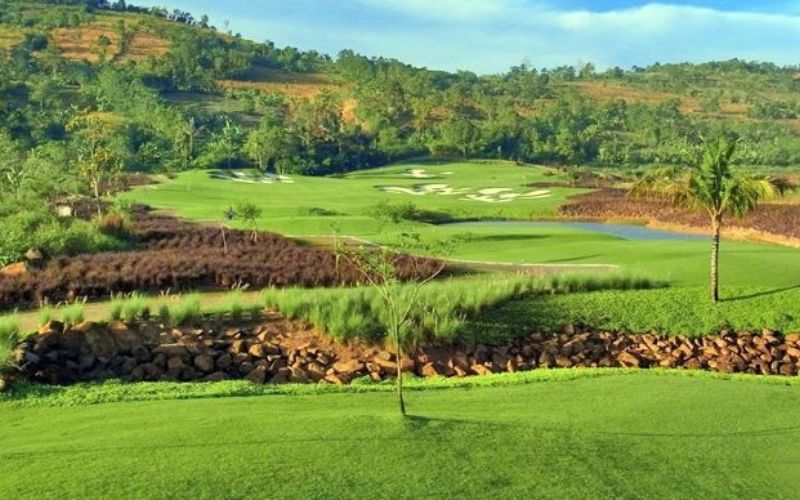 Scenic view of Padivalley Golf Club with green fairways, surrounding hills, and landscaped areas under a clear sky.