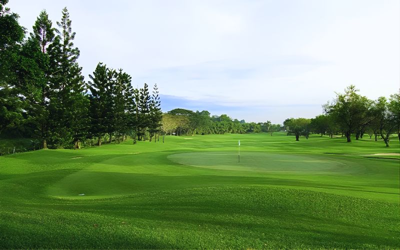 Palm Hills Golf Club in Hua Hin with lush green fairways, gentle slopes, and scenic mountain backdrop under a clear sky.