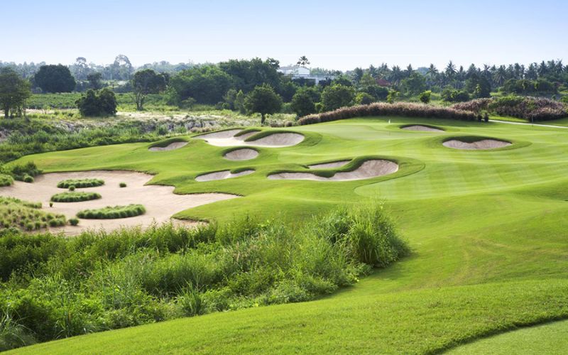 View of Phoenix Gold Golf and Country Club in Thailand, featuring rolling fairways, multiple sand bunkers, and lush greenery under bright daylight.