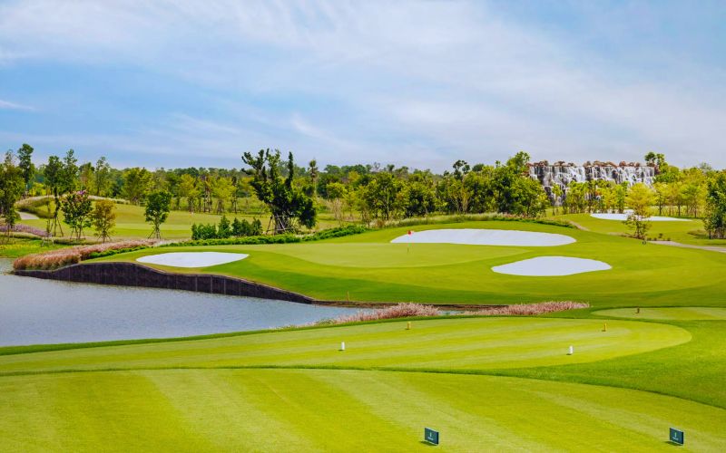 View of Robinswood Golf Club featuring a bright green fairway, sand bunkers, and a water hazard under a clear blue sky.