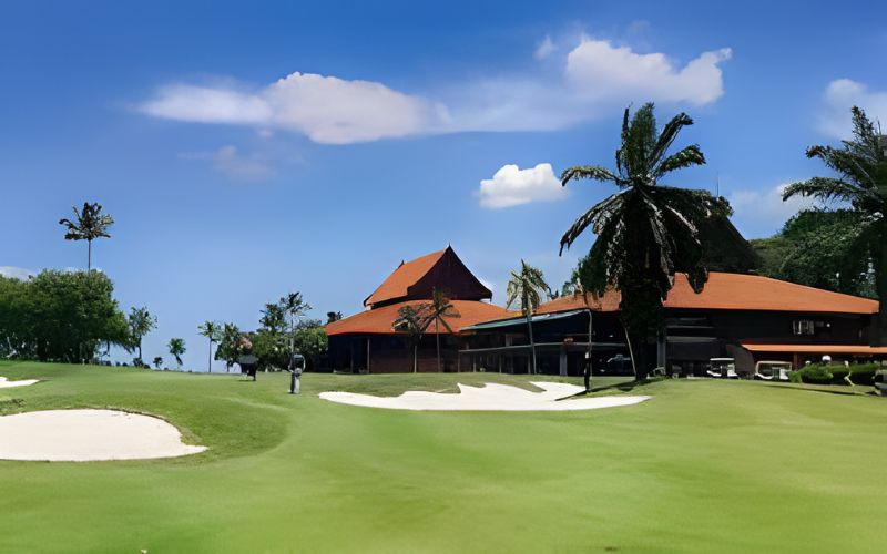 View of Saujana Golf & Country Club with lush green fairway and clubhouse under a blue sky.