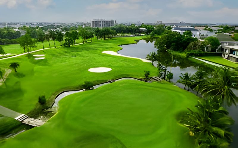 Aerial view of Summit Windmill Golf Club in Thailand, showcasing lush green fairways, water features, and surrounding tropical landscape under a bright sky.