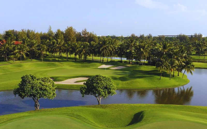 Beautiful golf course landscape at Thai Country Club surrounded by trees and lakes.