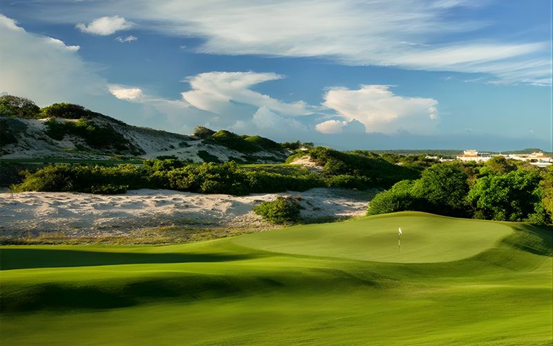Panoramic view of The Bluffs Ho Tram Strip golf course with rolling fairways, sand dunes, and blue coastal skies.