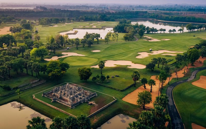 Aerial view of Vattanac Golf Resort West Course in Cambodia, showcasing lush fairways, water features, and Khmer-inspired architectural elements.