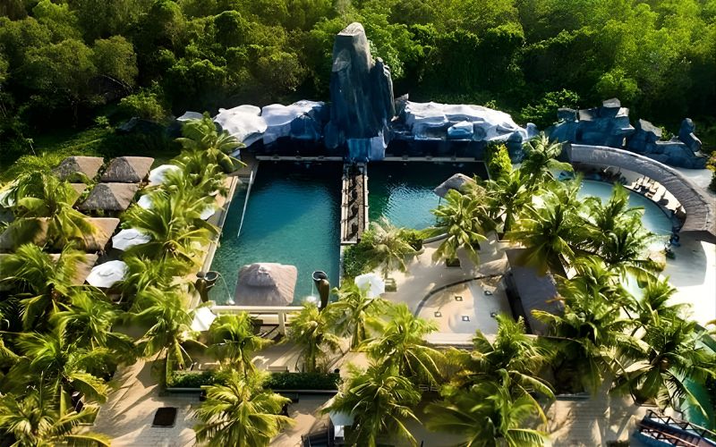 Aerial view of Binh Chau Hot Springs surrounded by lush tropical greenery, with clear blue pools and resort facilities nestled among palm trees.