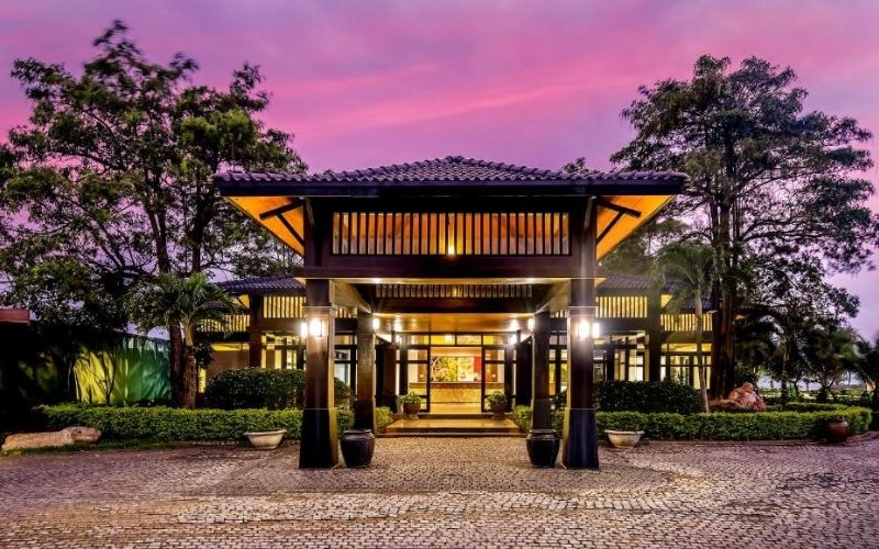 Green golf course landscape at Montgomerie Links Vietnam with a modern clubhouse, rolling fairways, and water features under a bright sky.