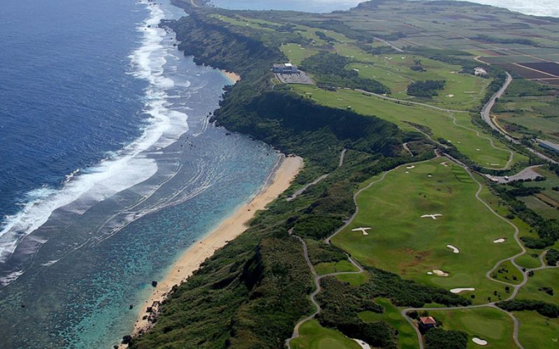 Aerial view of Miyakojima Ocean Golf Resort in Japan, highlighting the lush green fairways, coastal cliffs, and the blue ocean stretching along the horizon.