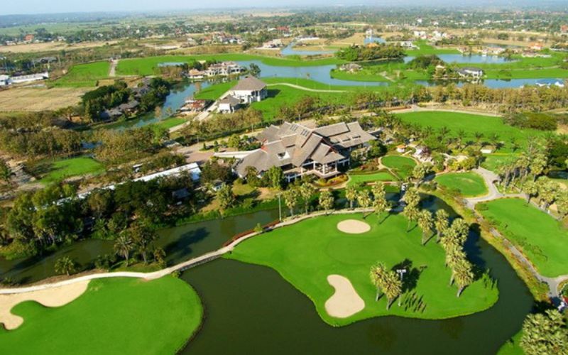 Aerial view of Summit Green Valley Chiang Mai Golf Course, featuring lush green fairways, sand bunkers, and a clubhouse surrounded by scenic mountain landscapes in northern Thailand.