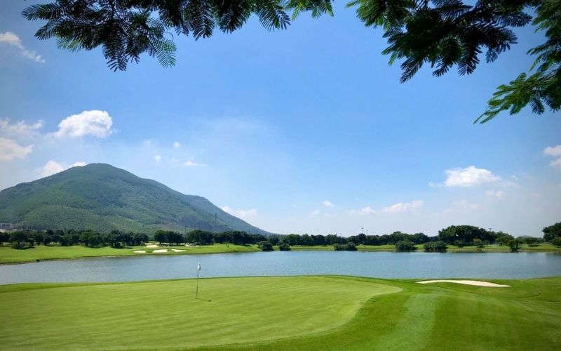 Tam Dao Golf Resort in northern Vietnam, surrounded by lush mountains, clear blue skies, and a serene lake
