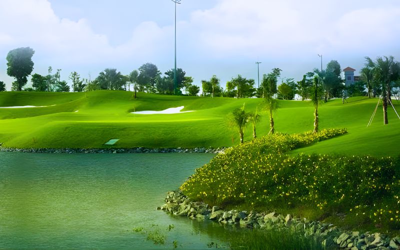 View of Tan Son Nhat Golf Course with bright green fairways, a calm water hazard, and landscaped edges under a clear sky.