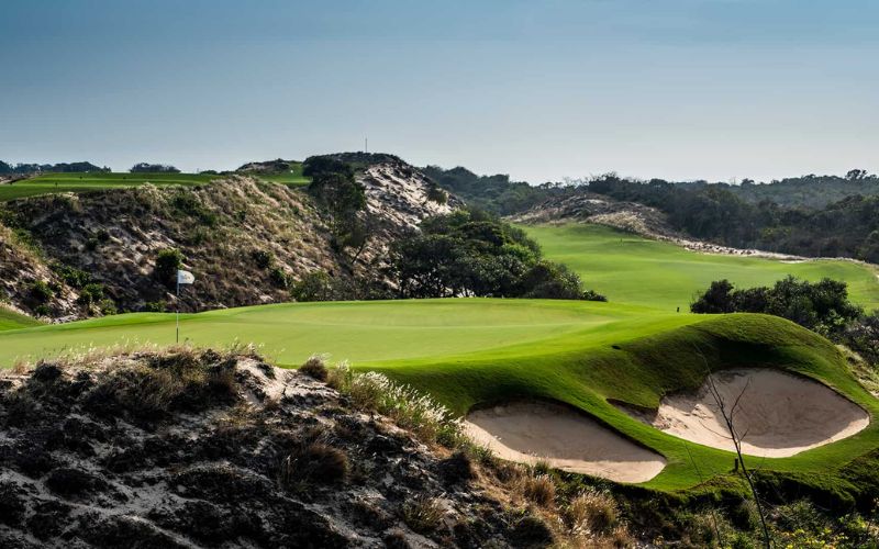 The Bluffs Ho Tram Strip golf course in southern Vietnam, featuring dramatic coastal dunes, lush fairways, and panoramic sea views