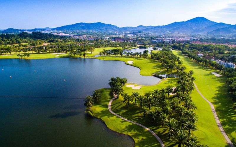Aerial view of Loch Palm Golf Club with lush fairways, water features and the city skyline in the background.