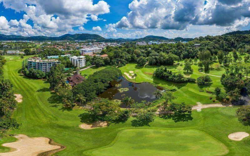 Aerial view of Phuket Country Club with lush fairways, water features and the city skyline in the background.