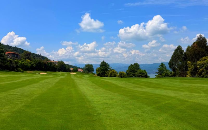 Green fairway in Shili Yunling Golf Club under blue sky , with mountain in the distance