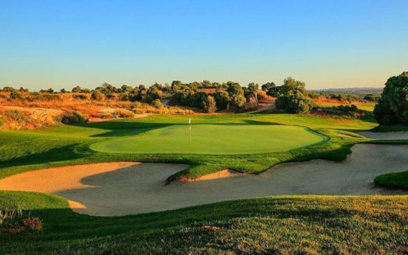 Sunset view of the fairway and sand bunkers at Beijing Honghua International Golf Club, with manicured greens and water features under warm evening light